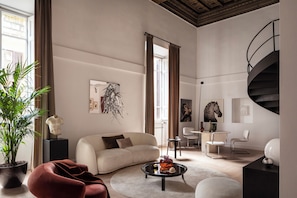 A modern living room with a sofa, coffee table, and chairs, a staircase, and a large plant. - Luxury apartment near the Spanish Steps (Roma)