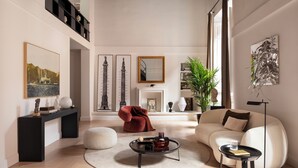 Un salon spacieux avec un plafond haut, une cheminée, un canapé, une table basse et une bibliothèque.