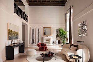 A spacious living room with a high ceiling, a fireplace, a sofa, a coffee table, and a bookshelf. - Luxury apartment near the Spanish Steps (Roma)