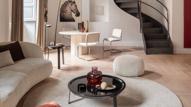 Un salon moderne avec un escalier à volutes, un canapé, une table basse et un coin repas.