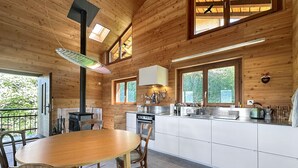 L’intérieur d’une cabane en bois comprend un coin repas, une cuisine et de grandes fenêtres.