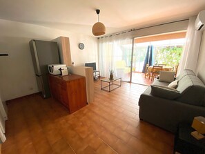 Ein Wohnzimmer mit einer Couch, einem Fernseher, einem Holzschrank und einem Essbereich mit Tisch und Stühlen.