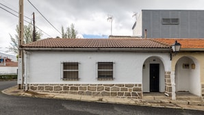 Un bâtiment blanc avec un toit en tuiles, une base en pierre et une porte noire.