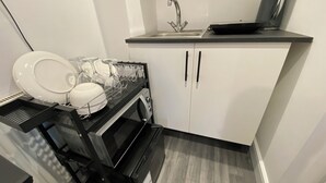 Una cocina compacta con un fregadero, un microondas y un escurreplatos.