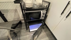 Una cocina equipada con microondas, escurreplatos y una silla.