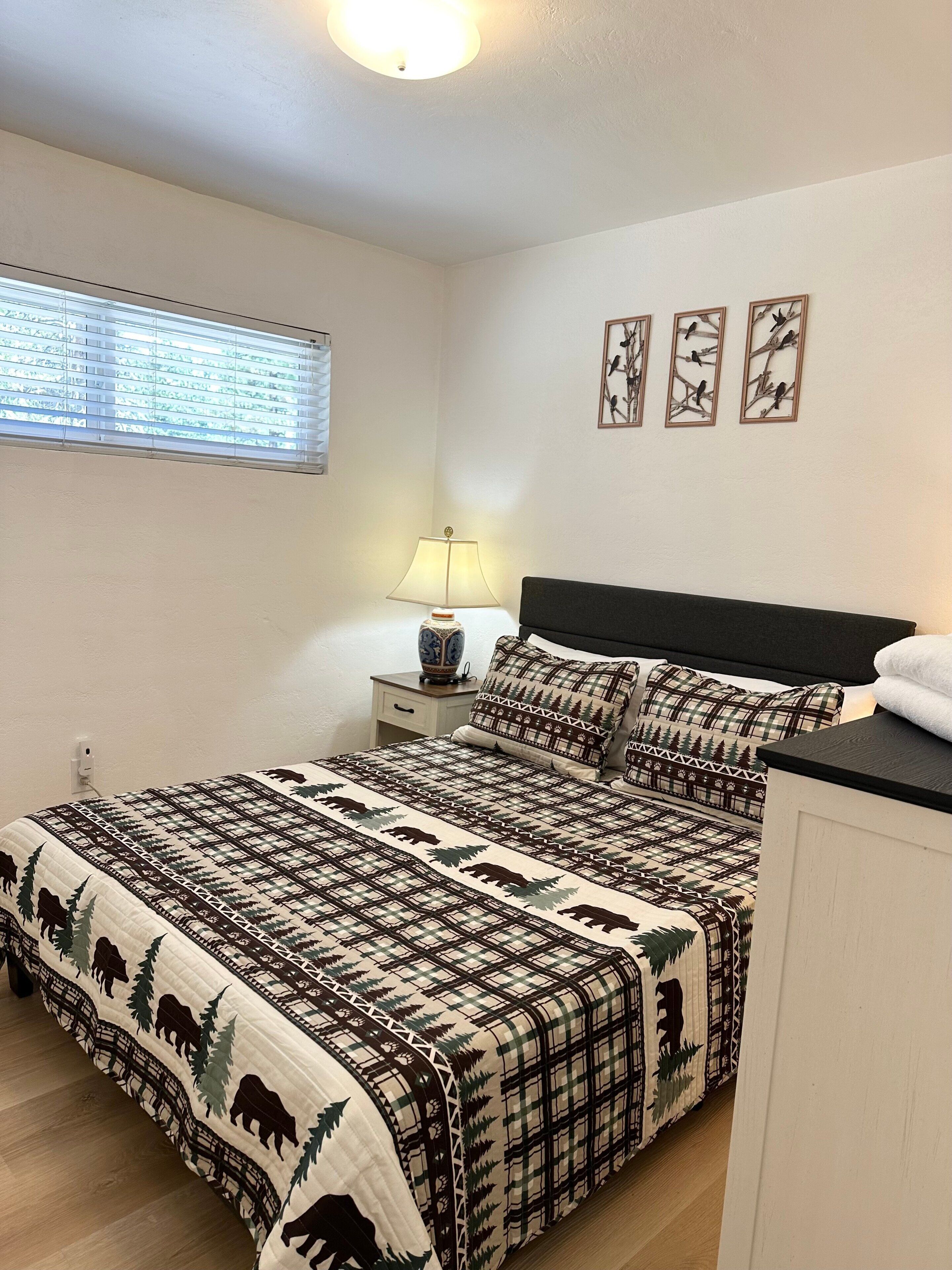 Un dormitorio con una cama, una mesita de noche, una lámpara y tres cuadros colgados en la pared.