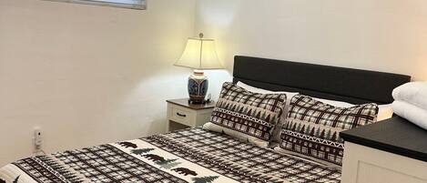 Un dormitorio con una cama, una mesita de noche, una lámpara y tres cuadros colgados en la pared.