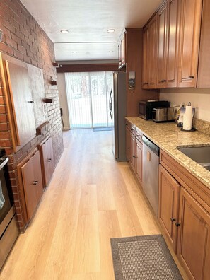 A kitchen with wooden cabinets, a refrigerator, a microwave, and a dishwasher. - Red Lake House | Spacious Tahoe Retreat on a Private 0.27 Acre Lot | HCH0681 (South Lake Tahoe)