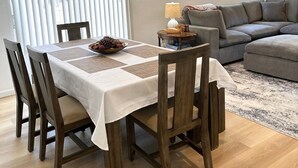 Comedor con una mesa dispuesta para cuatro personas, un sofá y una lámpara.