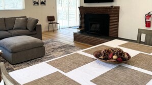 Una sala de estar con chimenea, un sofá, un televisor y una mesa de comedor con individuales.