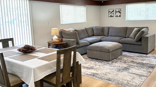 Una sala de estar con una mesa de comedor, un sofá gris y una alfombra.