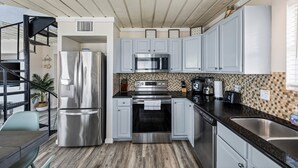 A modern kitchen with stainless steel appliances, light grey cabinets, and a checkered backsplash. - Beachfront | 3BR | Deck + Gulf Views (Galveston)