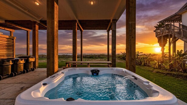A hot tub under a wooden pergola with a sunset view. - Beachfront | 3BR | Deck + Gulf Views (Galveston)