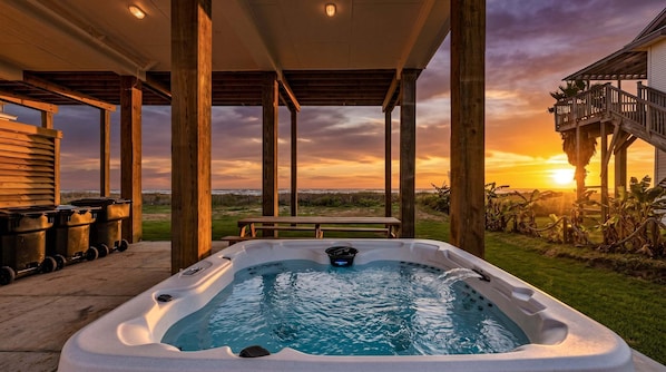 A hot tub under a wooden pergola with a sunset view. - Beachfront | 3BR | Deck + Gulf Views (Galveston)