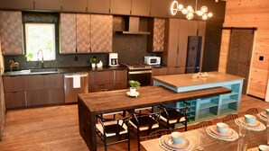 Een moderne keuken met houten kasten, een centraal eiland en een eethoek met vier stoelen en een gedekte tafel.
