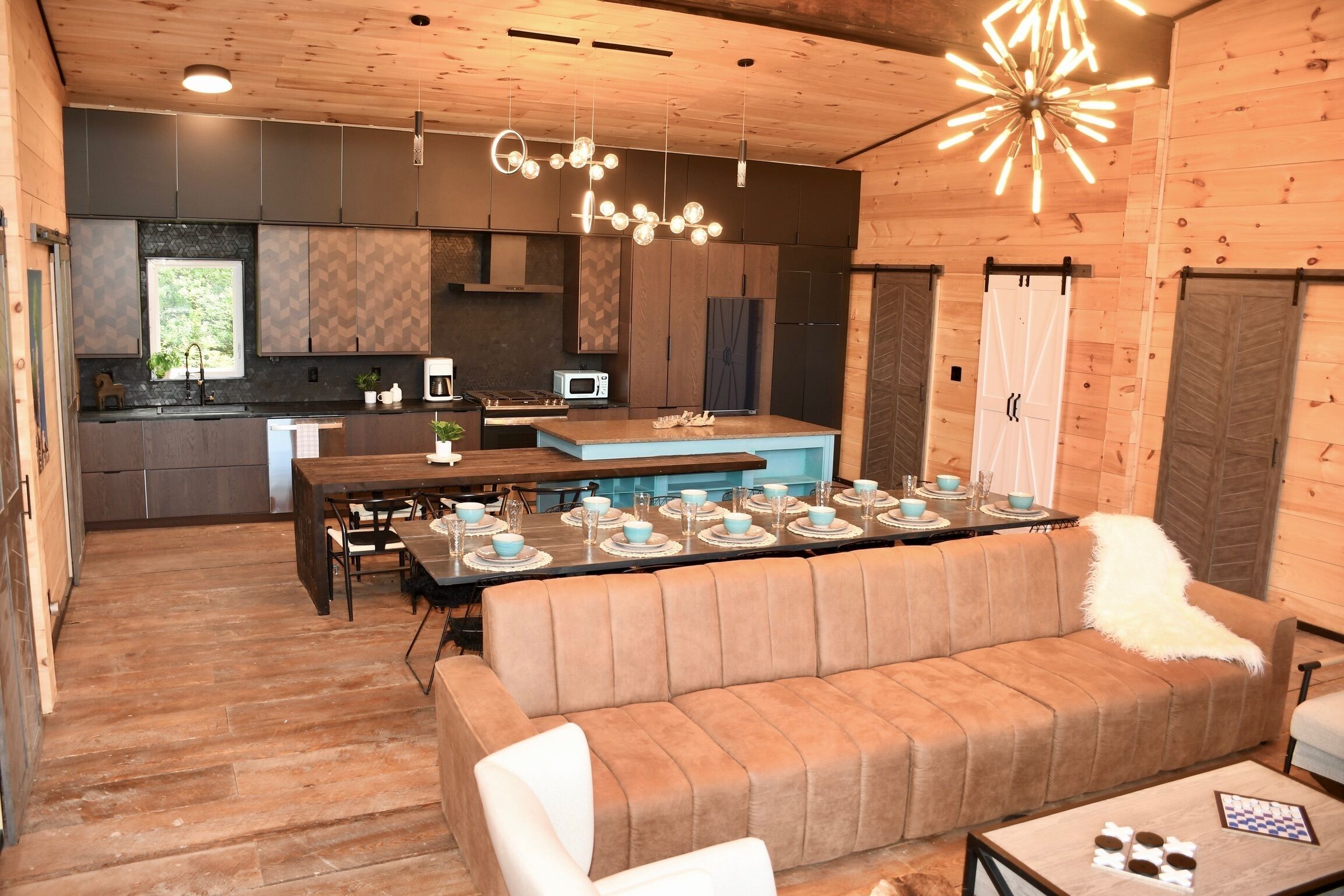 A modern kitchen with a dining area, wooden walls, and a central island.