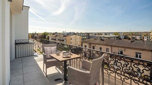 Un balcón con mobiliario de mimbre y una mesa, con vistas a una zona residencial con edificios.