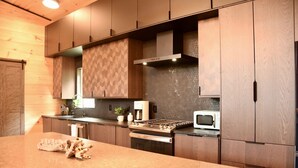 Una cucina moderna con mobili in legno, un piano di lavoro in granito, forno integrato e microonde.