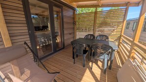 Een houten terras met een tafel, stoelen, een schuifpui en een houten omheining.