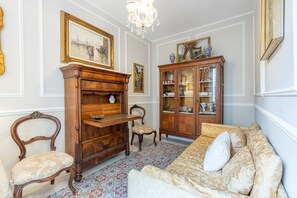 Ein Zimmer mit einer Couch, einem Holzschrank, einem Sessel und einer Pendelleuchte.