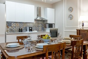 A dining area with a wooden table set for four, a kitchen with white cabinets and a tiled backsplash, and a microwave. - Spacious and elegant 150 sq m apartment, perfect for six people, located on the first floor of a period building with an elevator (NOT accessible to disabled guests).The property is located in the heart of Montecatini Terme's historic center (pedestrian  (Montecatini Terme)