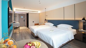 Habitación de hotel con dos camas, un escritorio y un baño.