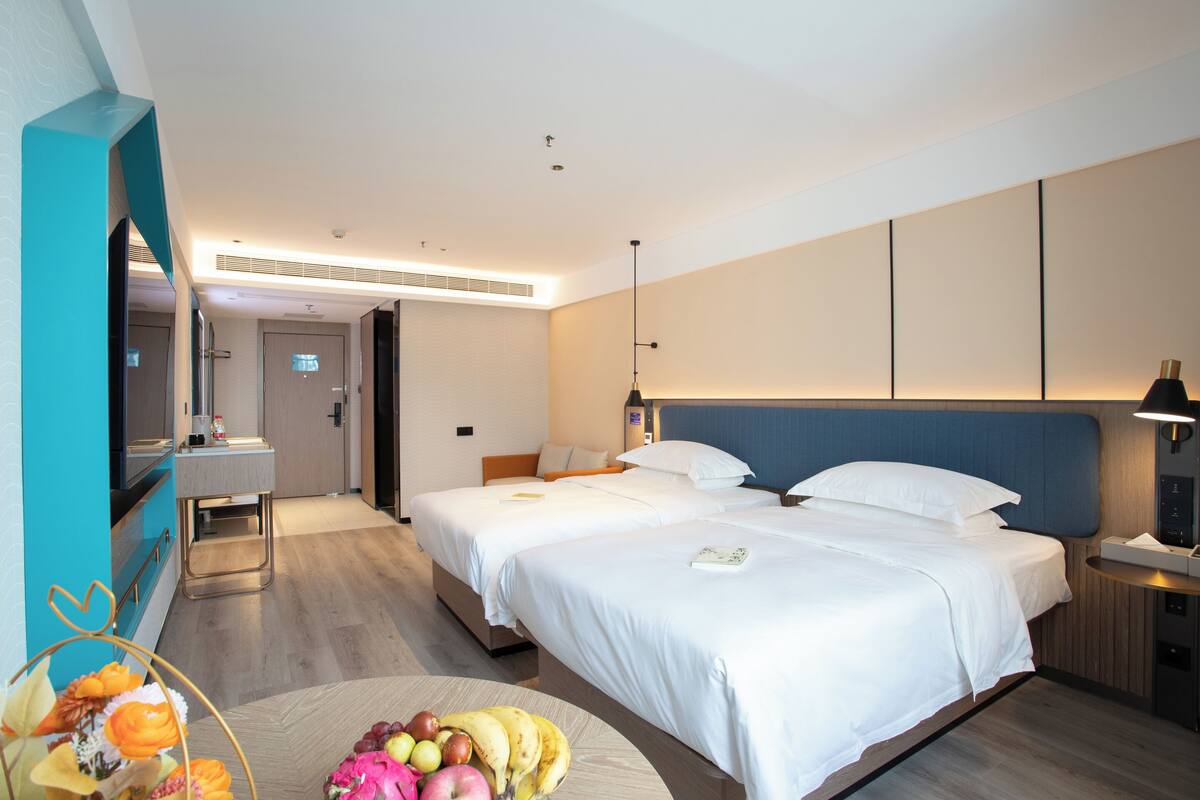 Habitación de hotel con dos camas, un escritorio y un baño.