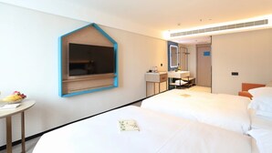Habitación de hotel con dos camas, una mesita con fruta, un espejo y un escritorio con lámpara.