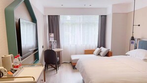 Habitación de hotel con cama, mesita de noche, silla, escritorio, televisor y cortinas.