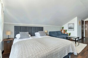 Ein Schlafzimmer mit einem großen Bett, einer Couch, einem Nachttisch, einer Lampe und einem gerahmten Bild an der Wand.