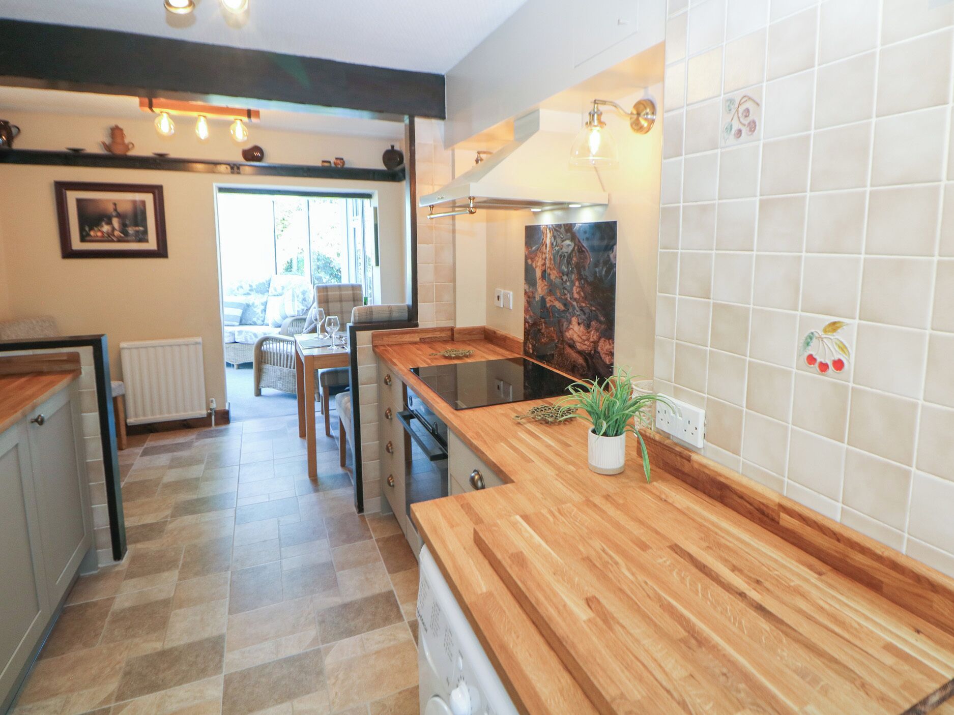 A kitchen with a wooden countertop, a radiator, a dining area with a table and chairs, and a view through a glass door.