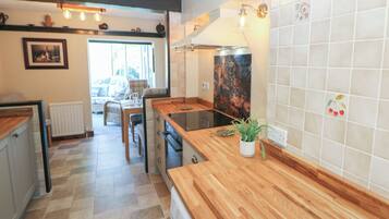 A kitchen with a wooden countertop, a radiator, a dining area with a table and chairs, and a view through a glass door.