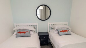 Habitación doble con dos camas, una mesita de noche, un espejo y una lámpara.