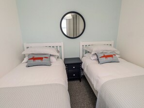 Ein Doppelzimmer mit zwei Betten, einem Nachttisch, einem Spiegel und einer Lampe.