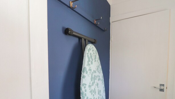 Una habitación con pared azul, una puerta y una tabla de surf colgada en la pared.