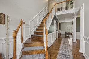 Un escalier avec des rampes en bois et des marches recouvertes de moquette, menant à un deuxième étage.