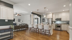 A modern kitchen with white cabinets, a central island with bar stools, a built-in oven, and a ceiling fan. - Spacious home in safe and accessible area! Close to Hull Street, TurnPike, & RVA (Midlothian)