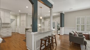 A spacious kitchen with white cabinetry, a central island with stools, and a dining area with a couch. - Spacious home in safe and accessible area! Close to Hull Street, TurnPike, & RVA (Midlothian)