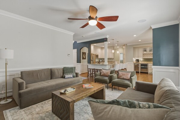 A living room with a sofa, armchairs, a coffee table, and a ceiling fan.