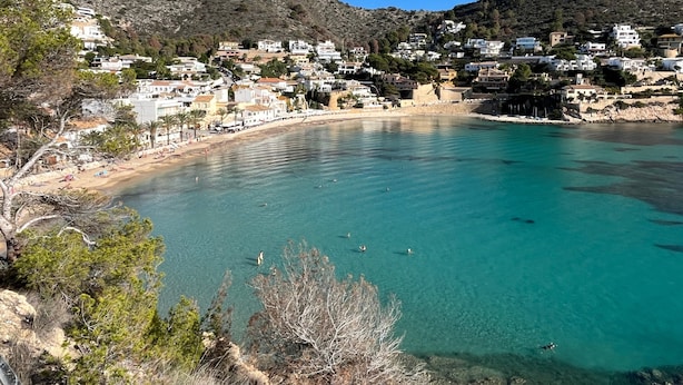 Uma vila costeira com edifícios à beira-mar e vista clara para o mar.