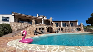 Piscina com um flutuador de flamingo rosa, degraus de pedra e um muro de pedra.