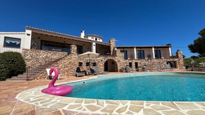 A pool with a pink flamingo float, stone steps, and a stone wall. - Villa 'Sobre Las Rocas' with Sea View, Pool, and Close to the Beach (Calpe)