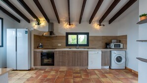 Uma cozinha moderna com vigas de madeira, forno embutido, máquina de lavar louça, máquina de lavar roupa e janela com vista.