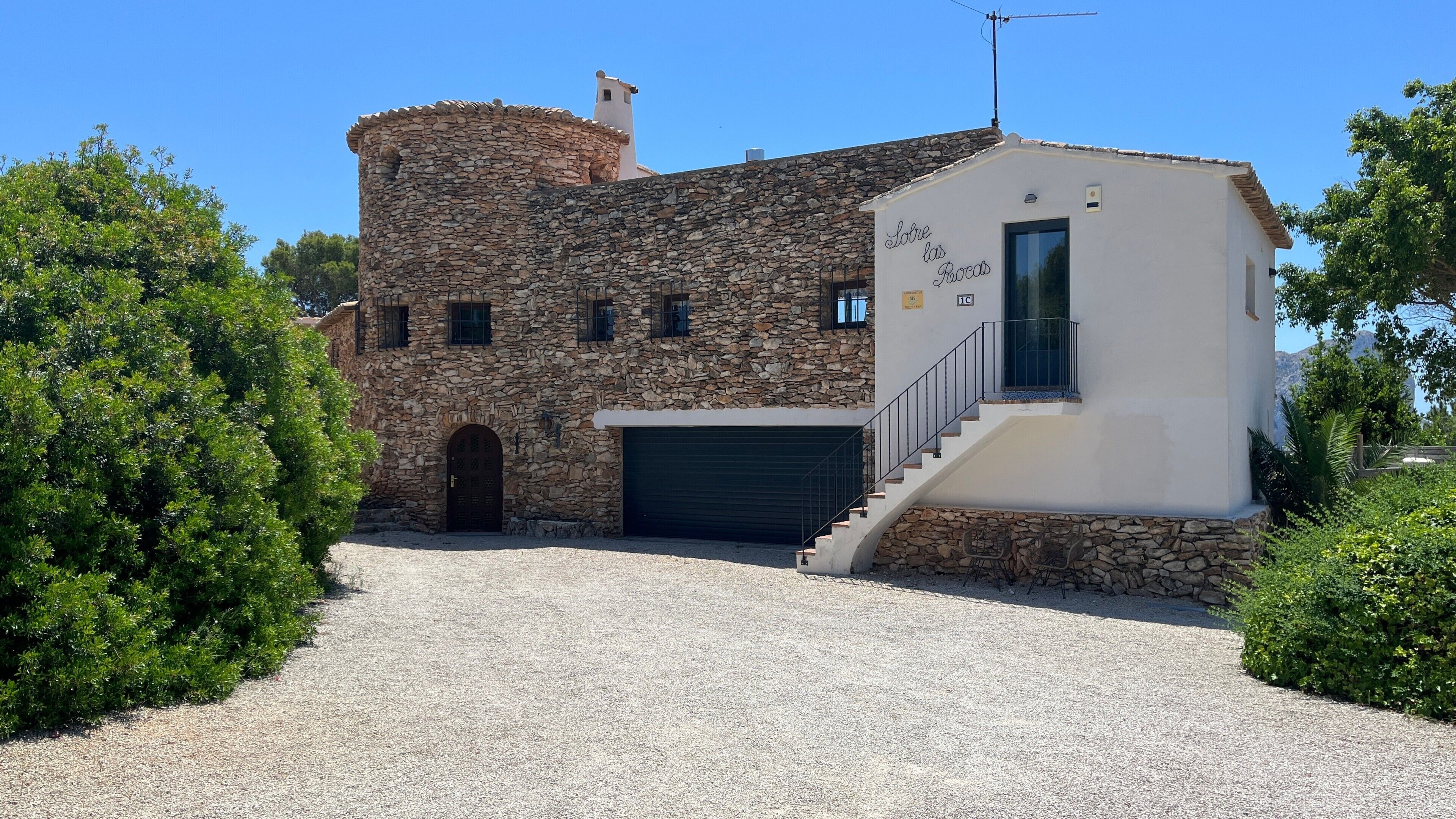 A stone building with a modern extension, a garage, and a staircase leading to the entrance.