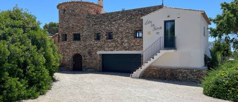 A stone building with a modern extension, a garage, and a staircase leading to the entrance.