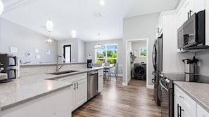A modern kitchen with a central island, built-in appliances, and a view to the outdoors. - Welcome to Villa Sunrise, 3 king bedrooms, pool and gas firepit table (Englewood)