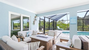 A covered outdoor seating area with a pool, furnished with sofas and chairs, and a sign welcoming guests. - Welcome to Villa Sunrise, 3 king bedrooms, pool and gas firepit table (Englewood)