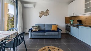 Ett kompakt bostadsutrymme med en soffa, ett matbord och ett köksområde.