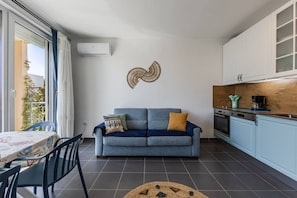 Ett kompakt bostadsutrymme med en soffa, ett matbord och ett köksområde.