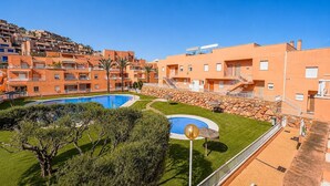 Un edificio residencial con piscina, un muro de piedra y un pequeño jardín.